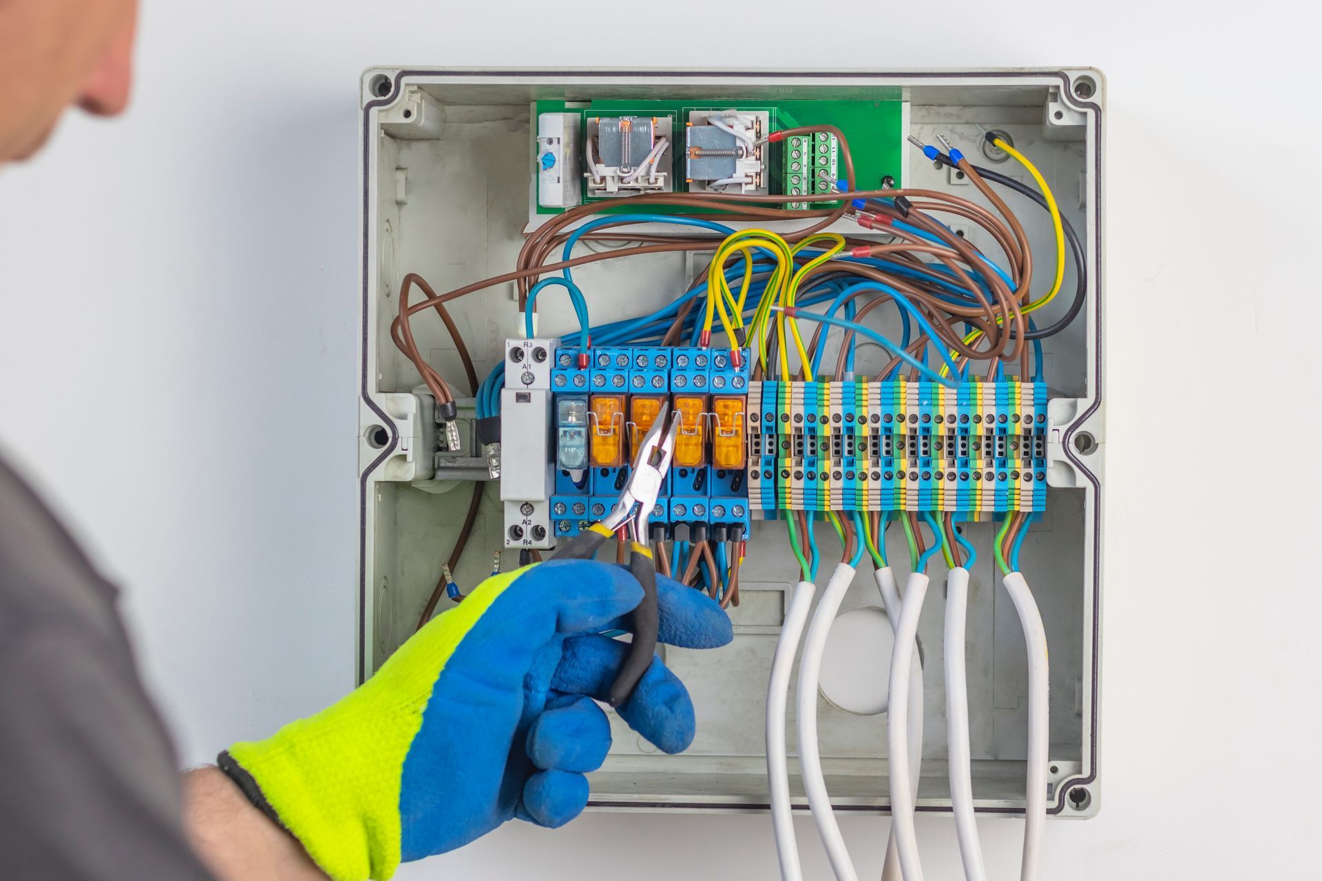 A man is working on an electrical box with a screwdriver.