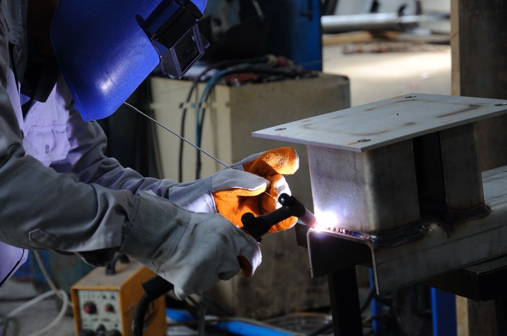 Welder Wearing a Blue Helmet and Gloves, Welding Metal in A Workshop — Chris Horton Manufacturing in Bathurst, NSW