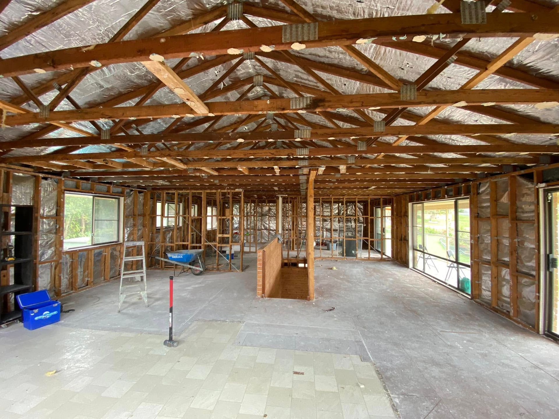 Interior of a house undergoing renovation. Exposed wooden beams and framing; visible insulation and concrete floor. — Barrington Coast Homes in Tallwoods, NSW