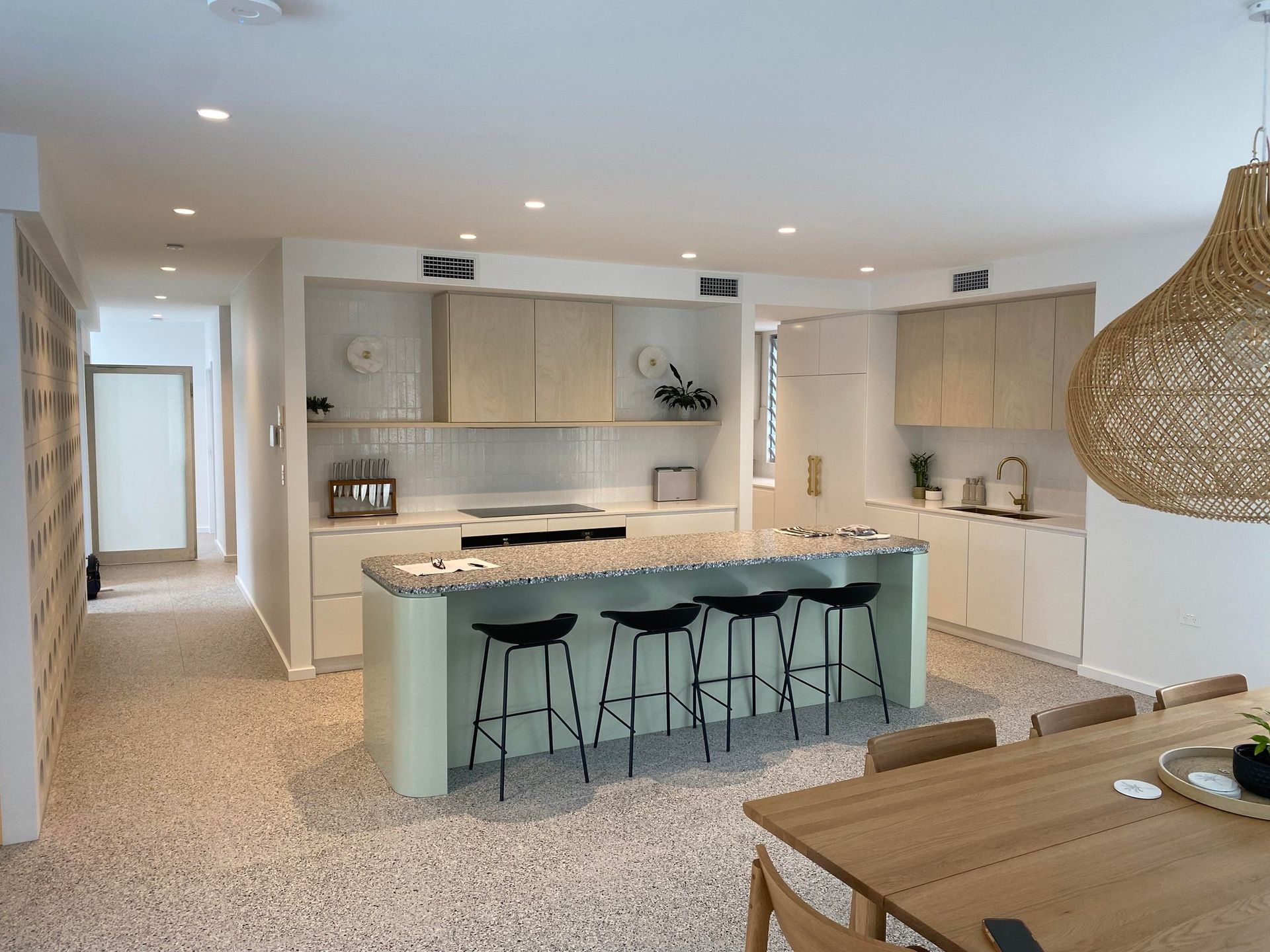 Modern kitchen with light green island, neutral cabinets, and terrazzo floors; dining area visible — Barrington Coast Homes in Tallwoods, NSW