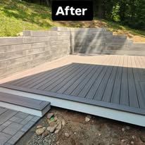 After: raised gray composite deck with steps beside a stone retaining wall and rocky ground