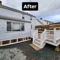 After: white house exterior with a small deck, white railing, and stairs on gravel.