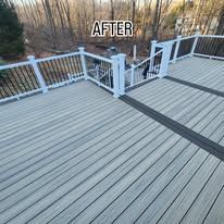 After: renovated gray deck with white railings and stairs overlooking a wooded yard