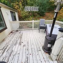 Before view of a weathered white wooden deck with railings, patio chair, and outdoor stove