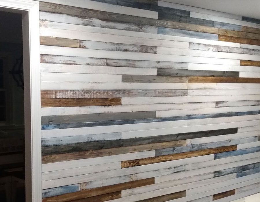 A wall covered in horizontal wooden planks of varying widths in shades of white, natural brown, and grey.