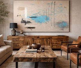 Modern living room with a long wood console, abstract art, coffee table, and leather chairs in a neutral-toned space.
