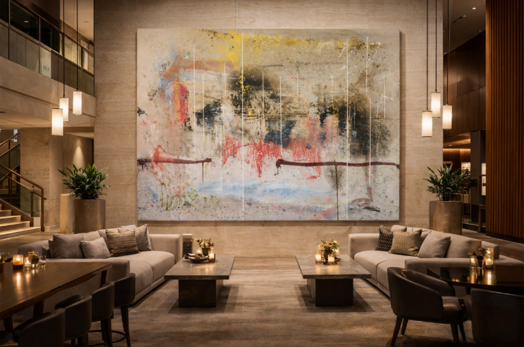 Three people viewing a large wall art display in a modern office meeting room