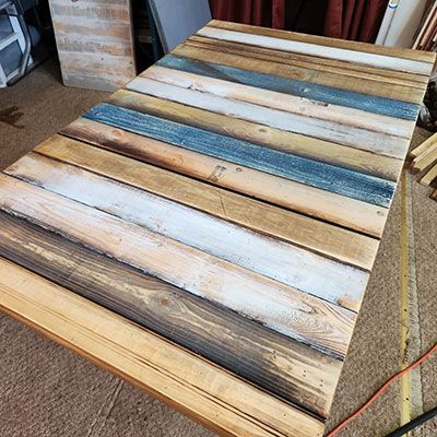 Weathered multicolor wooden plank tabletop with blue, white, and tan slats indoors