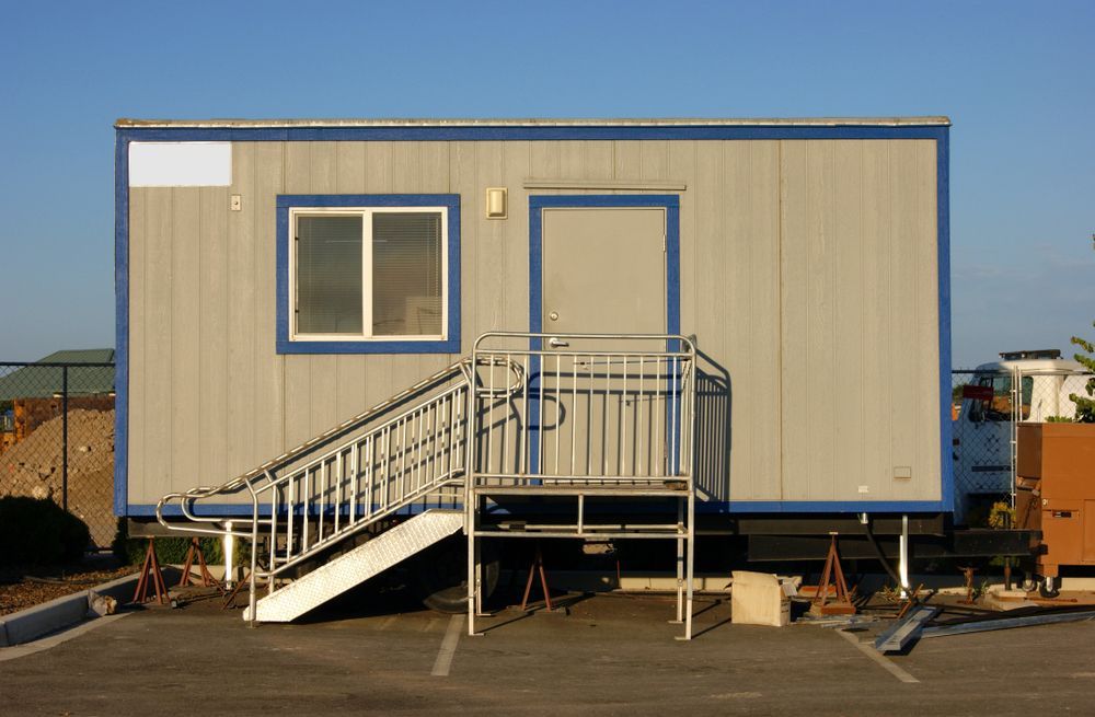 A person wearing yellow rubber gloves is cleaning a white wall with a blue cloth.