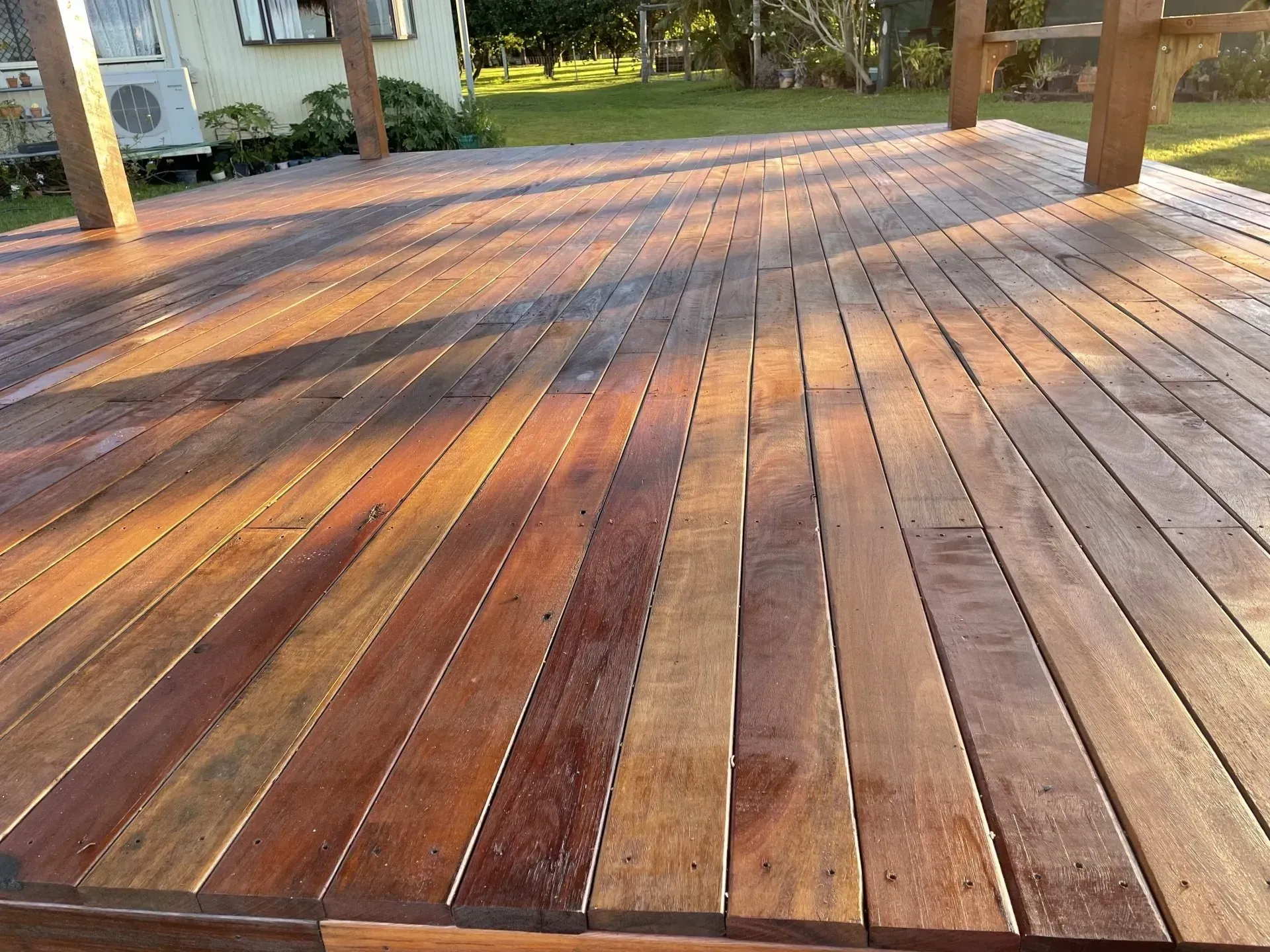 Wooden deck, newly stained with varying shades of brown, in a backyard — Boundary Creek Timber in Wallaville, QLD