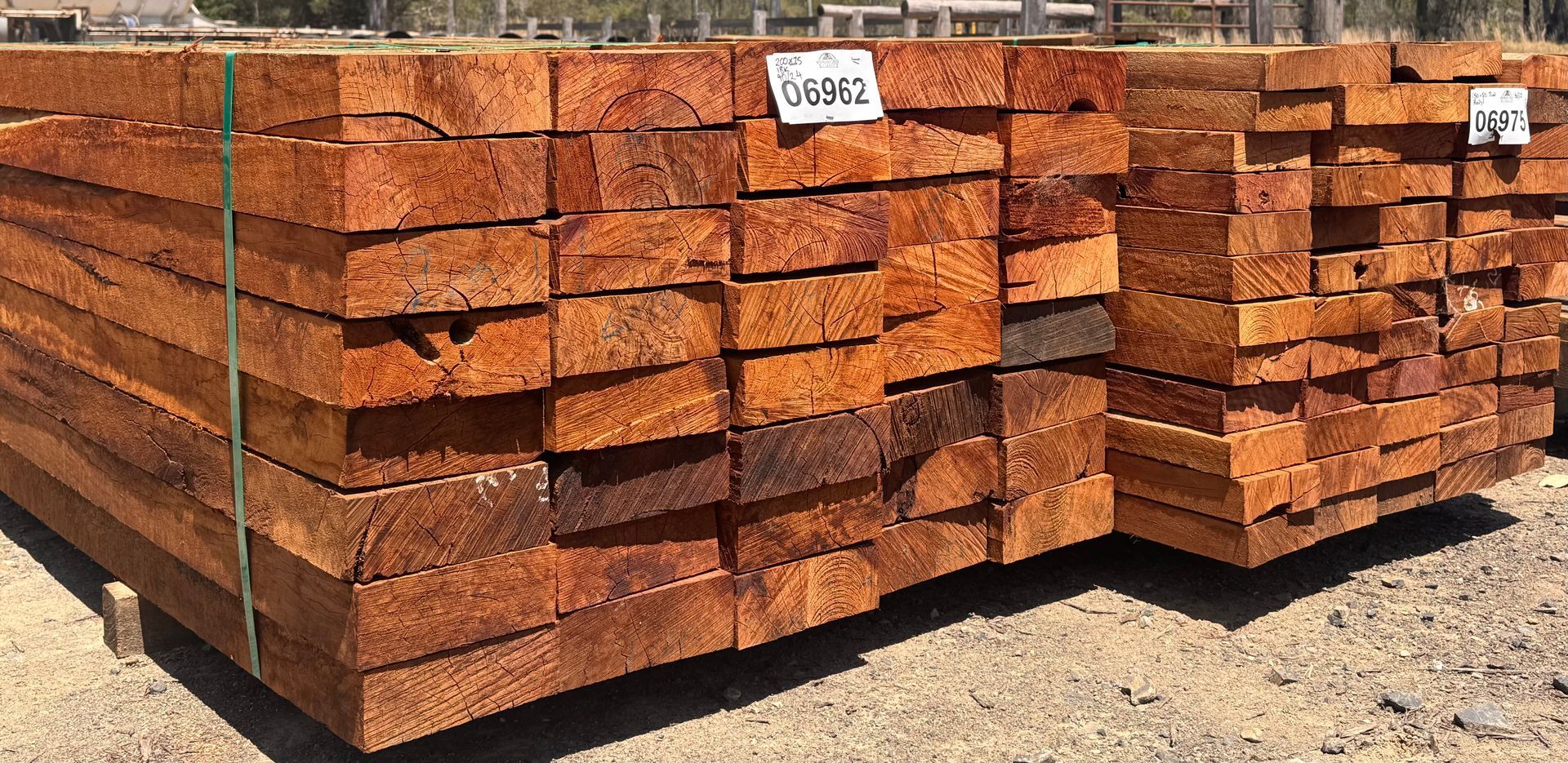 Stack of weathered, rectangular wooden beams, varying colors of brown, tan, and dark red — Boundary Creek Timber in Wallaville, QLD