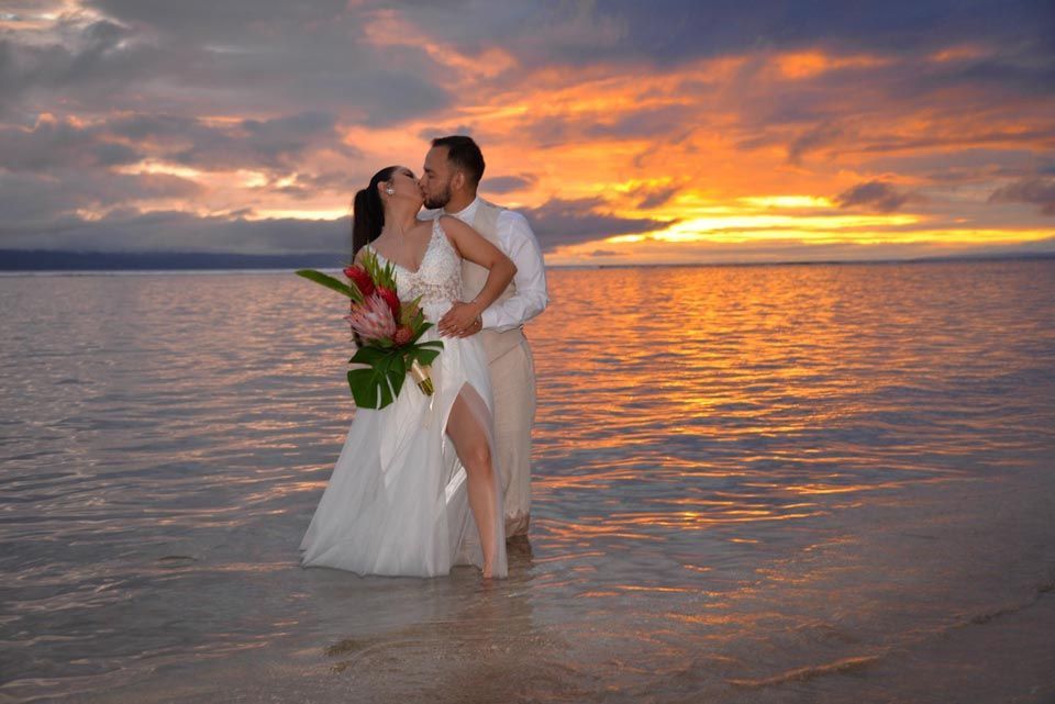 couple posing in water on beach at sunset