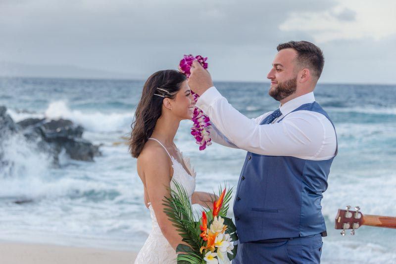 man putting lei on woman on beach