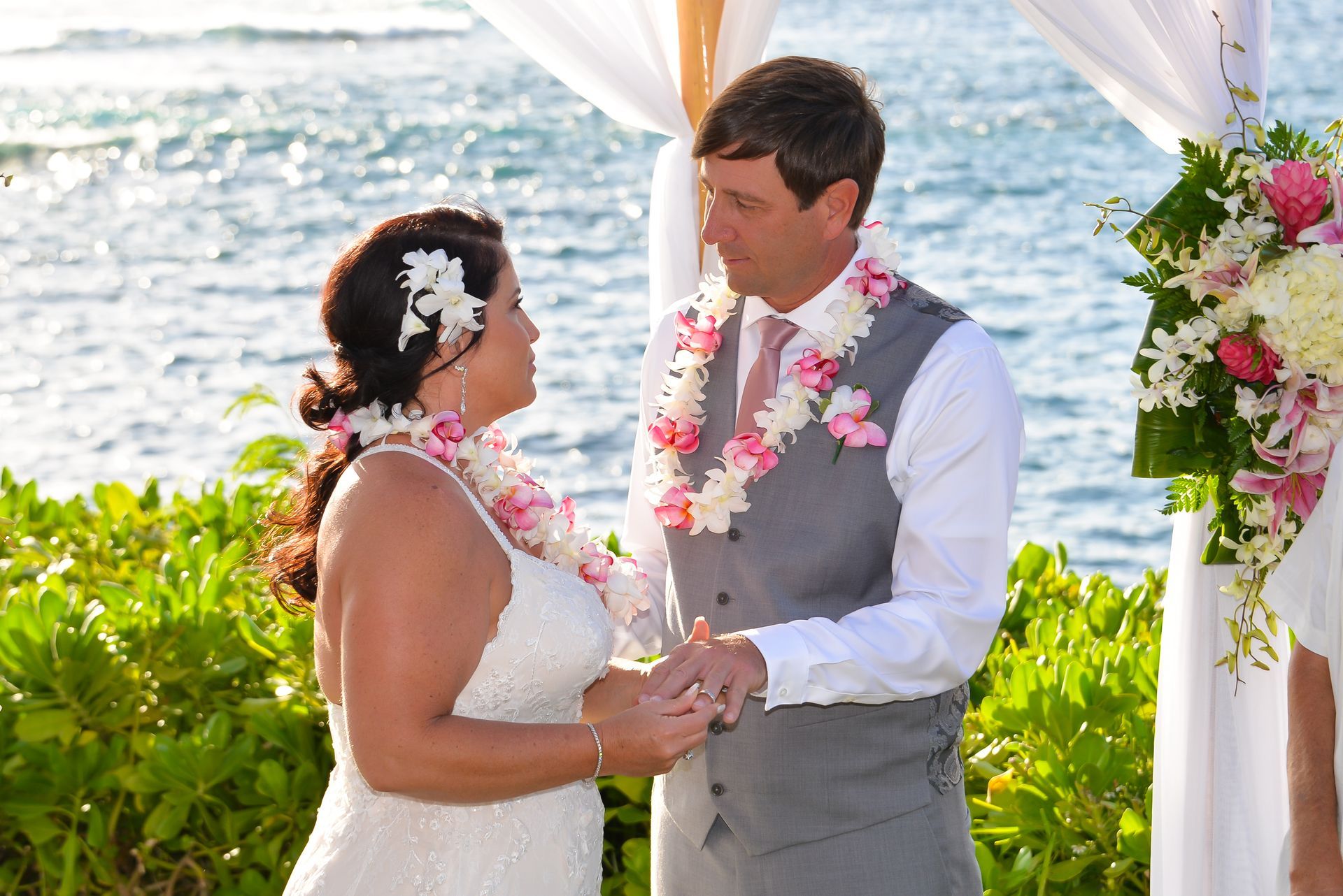 Bride and groom at an outdoor wedding ceremony, exchanging vows by the ocean.