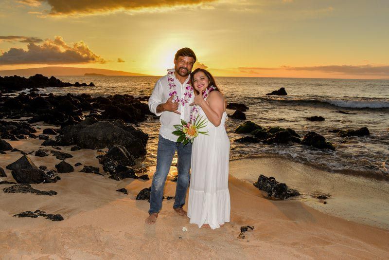 happy couple standing on beach at sunset