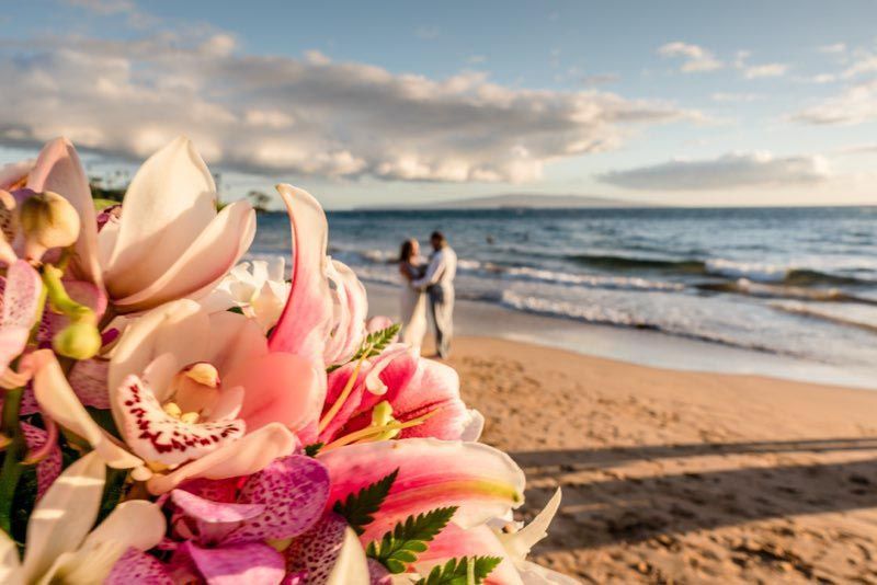 happy couple in background with flowers in foreground