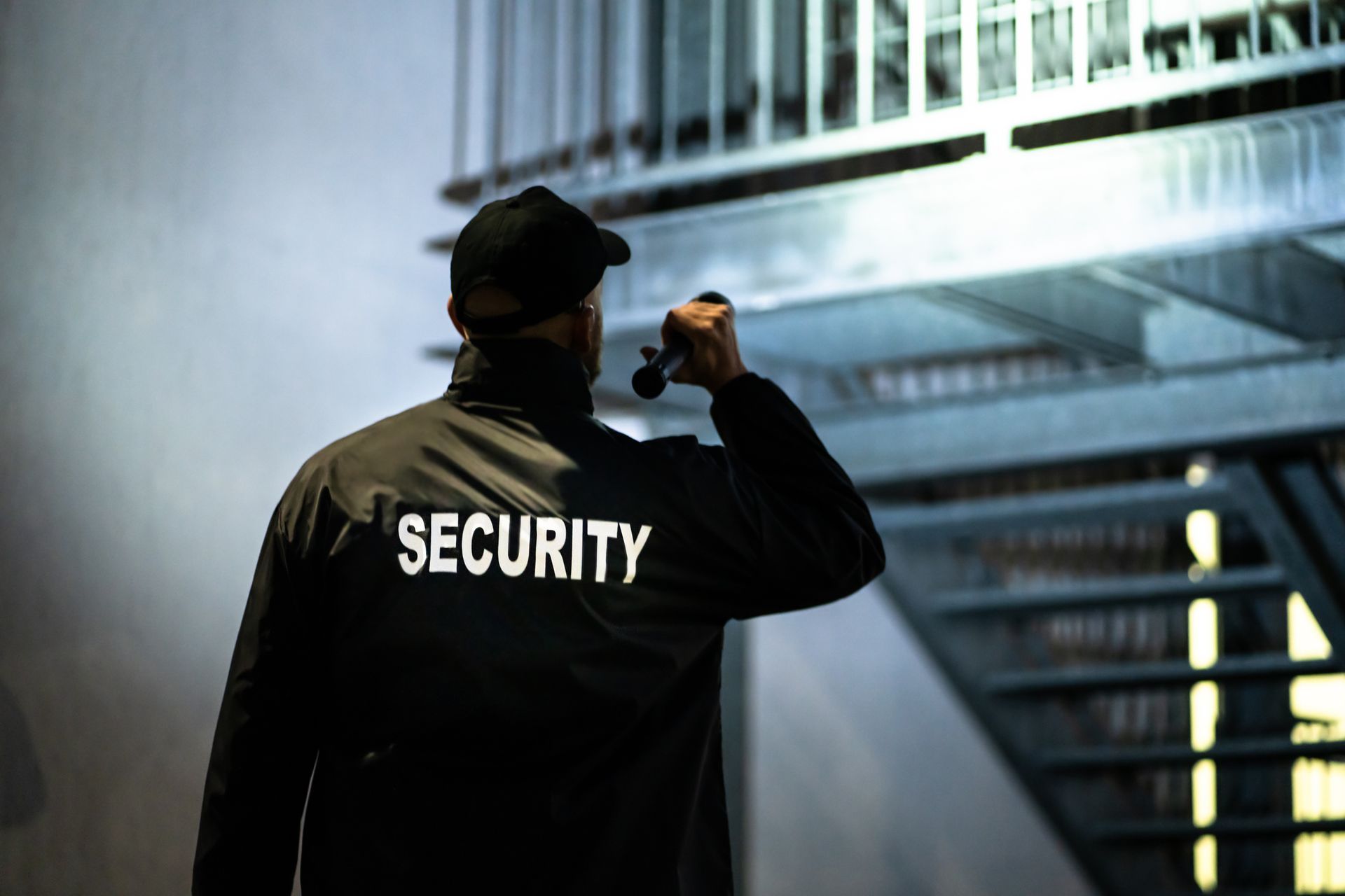 Security guard with flashlight inspecting a staircase in a building.