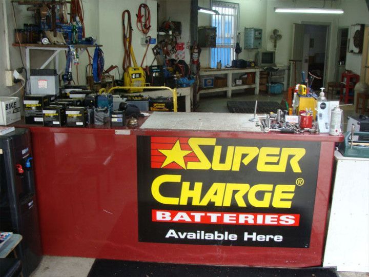 Auto repair shop counter with red Super Charge battery sign and tools in the background