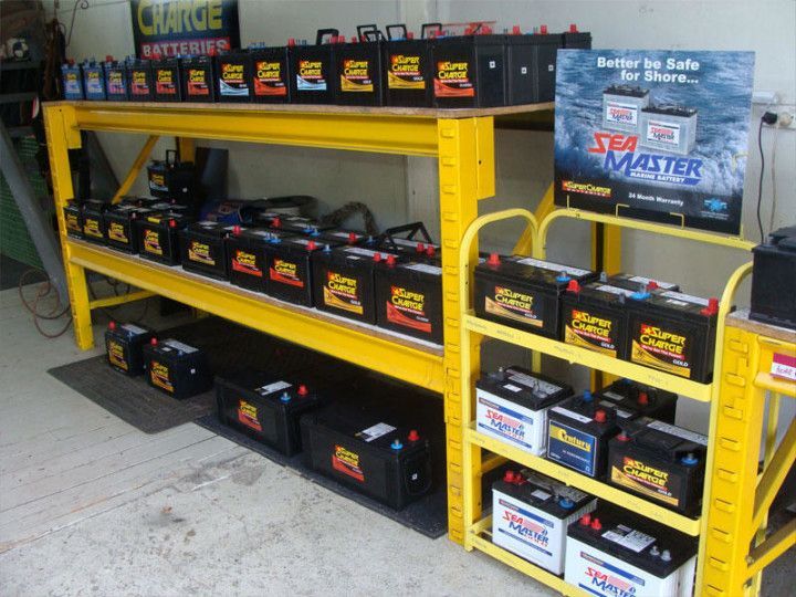 Yellow shelving filled with black batteries in a store aisle