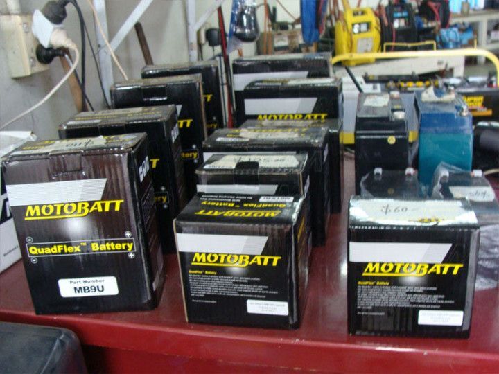Rows of Motobatt motorcycle batteries on a cluttered workshop floor