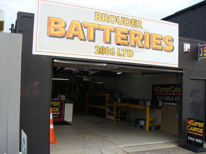 Broder Batteries storefront with open garage bay and bright yellow sign