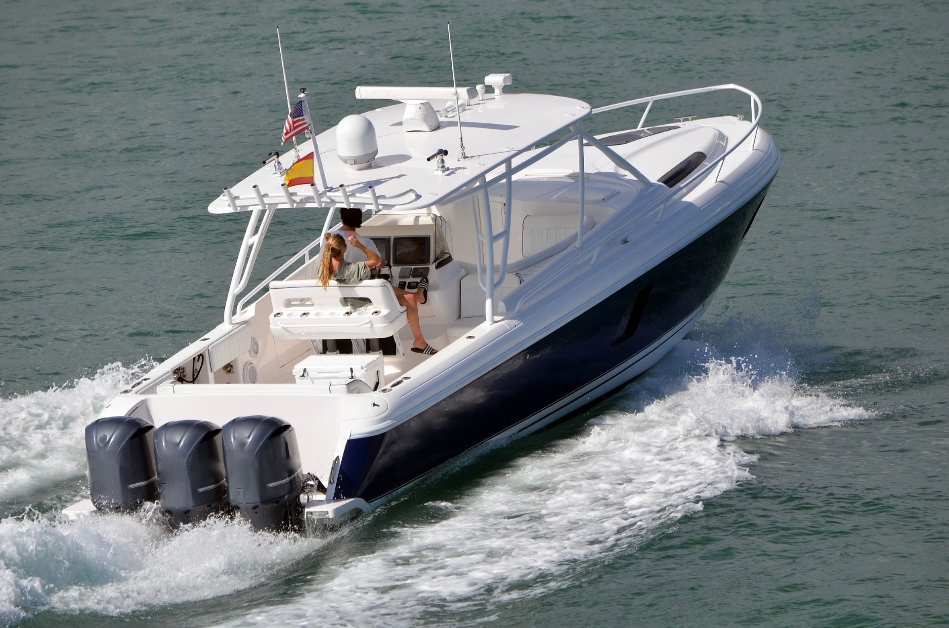 White motor yacht speeding across the water, leaving a foamy wake behind it.
