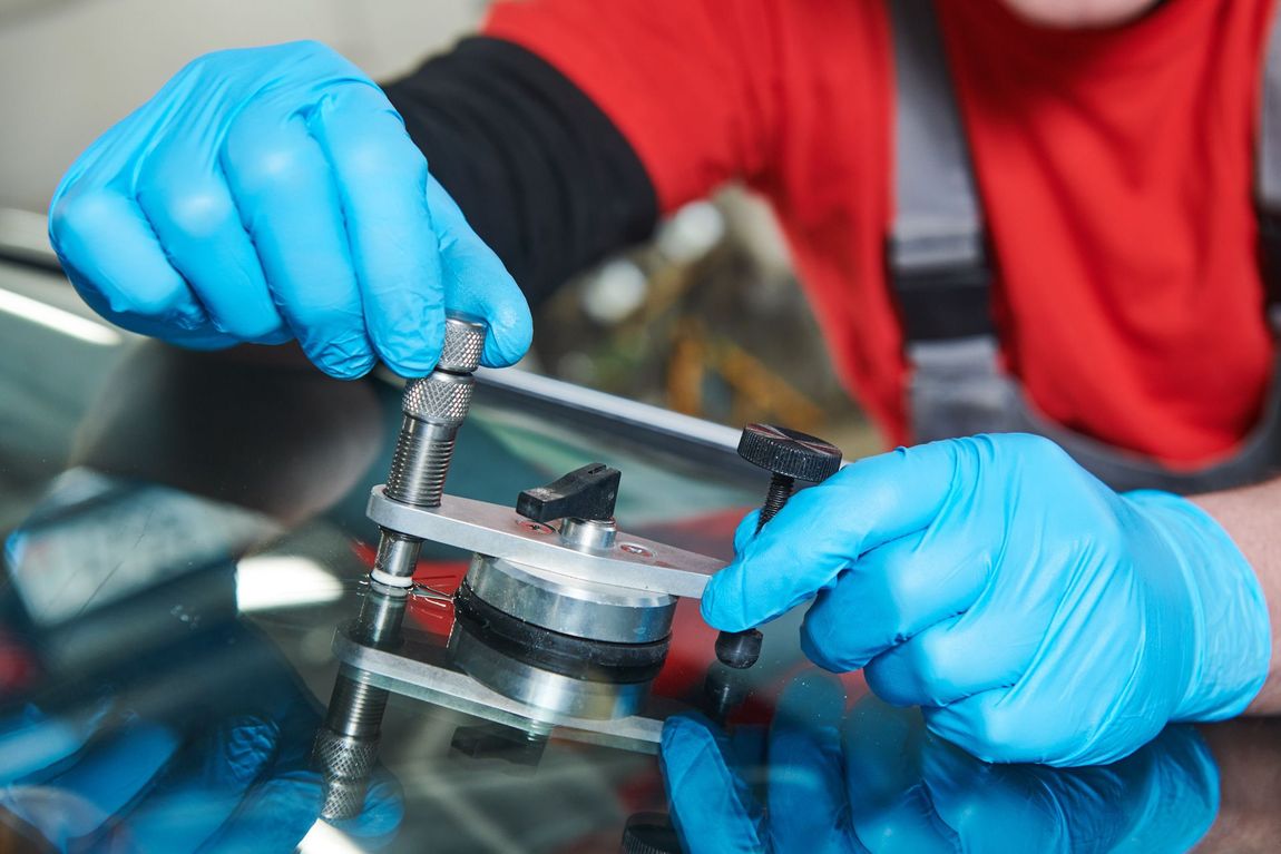 Blue-gloved hands adjusting a metal clamp on a clear cylindrical device with a red background.