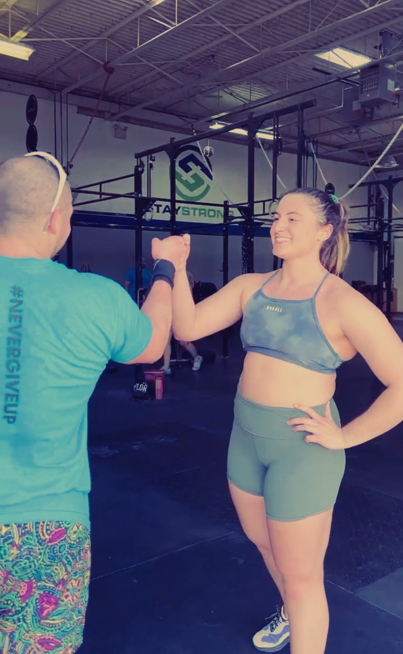 A man and a woman are giving each other a high five in a gym.