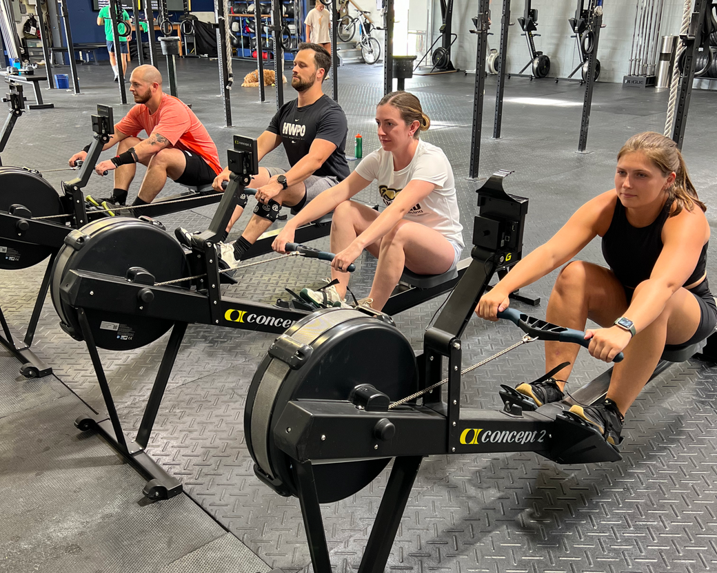 A group of people are lifting barbells in a gym.