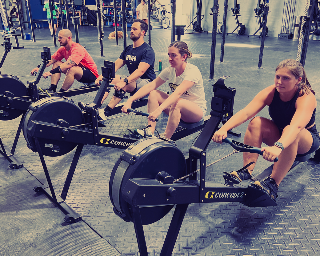 A group of people are lifting barbells in a gym.