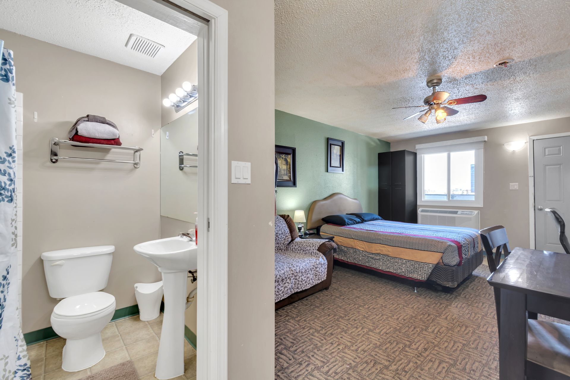 A bedroom with a toilet , sink , and ceiling fan.