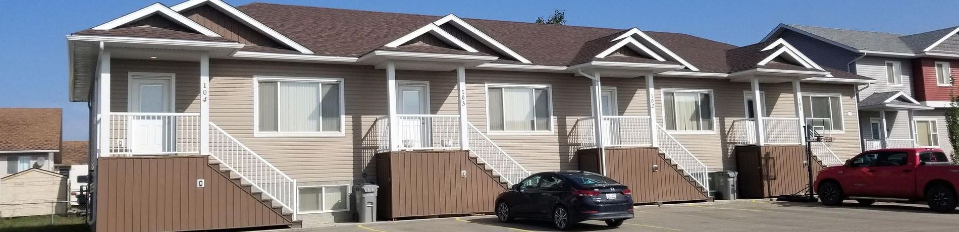 A row of houses with cars parked in front of them.