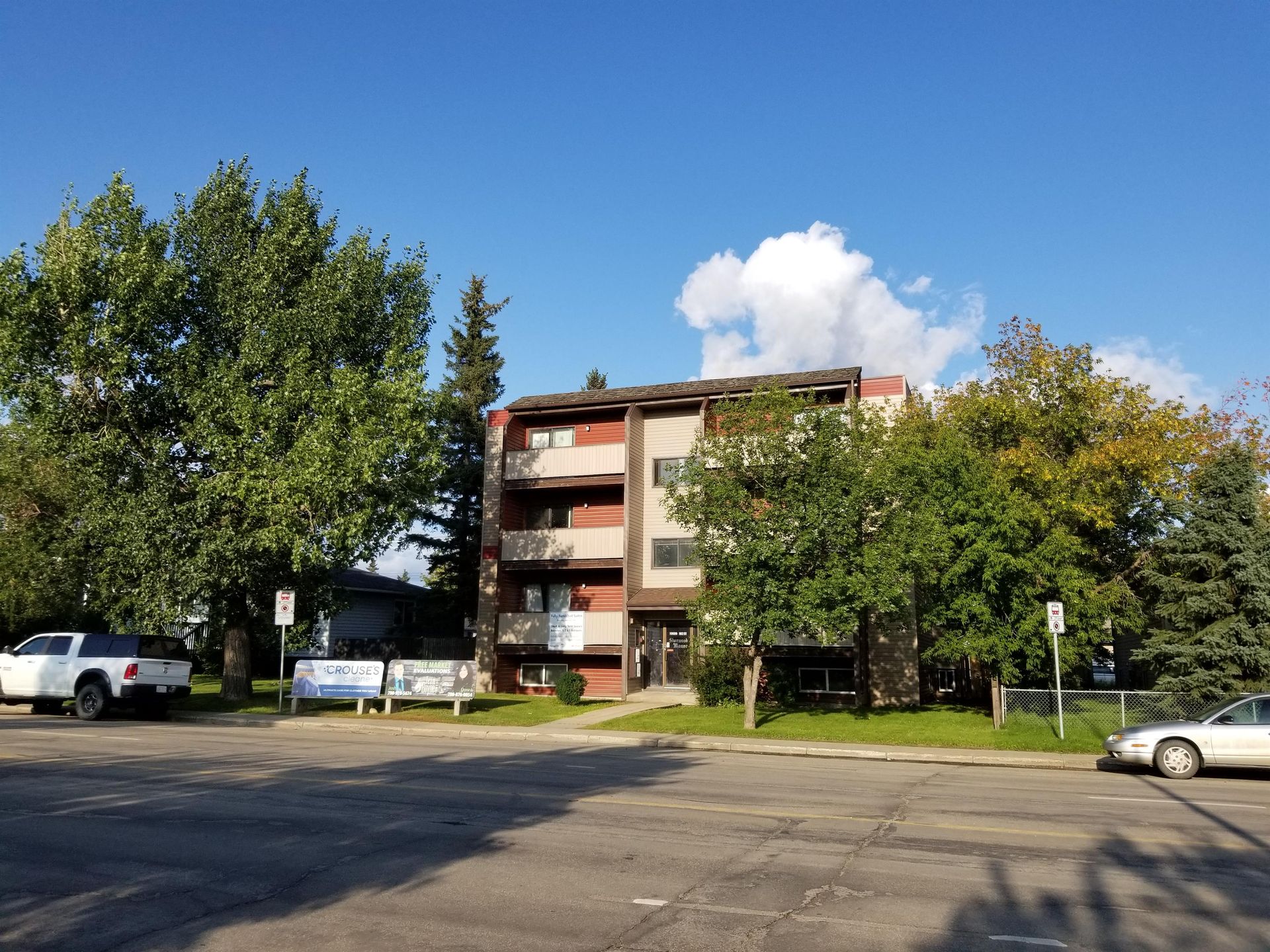 A parking lot in front of a building with cars parked in front of it.
