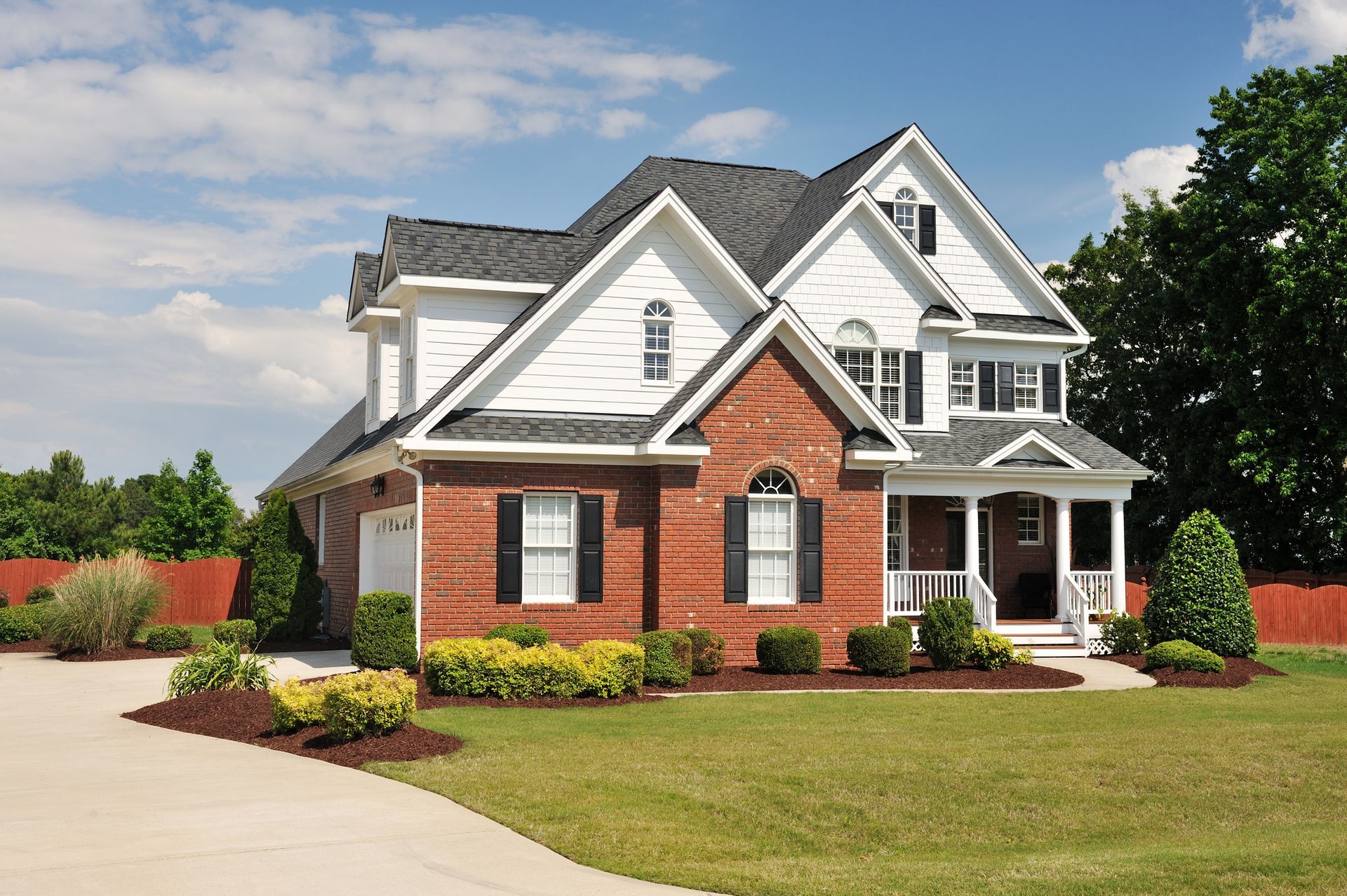 A large brick house with white siding and black shutters