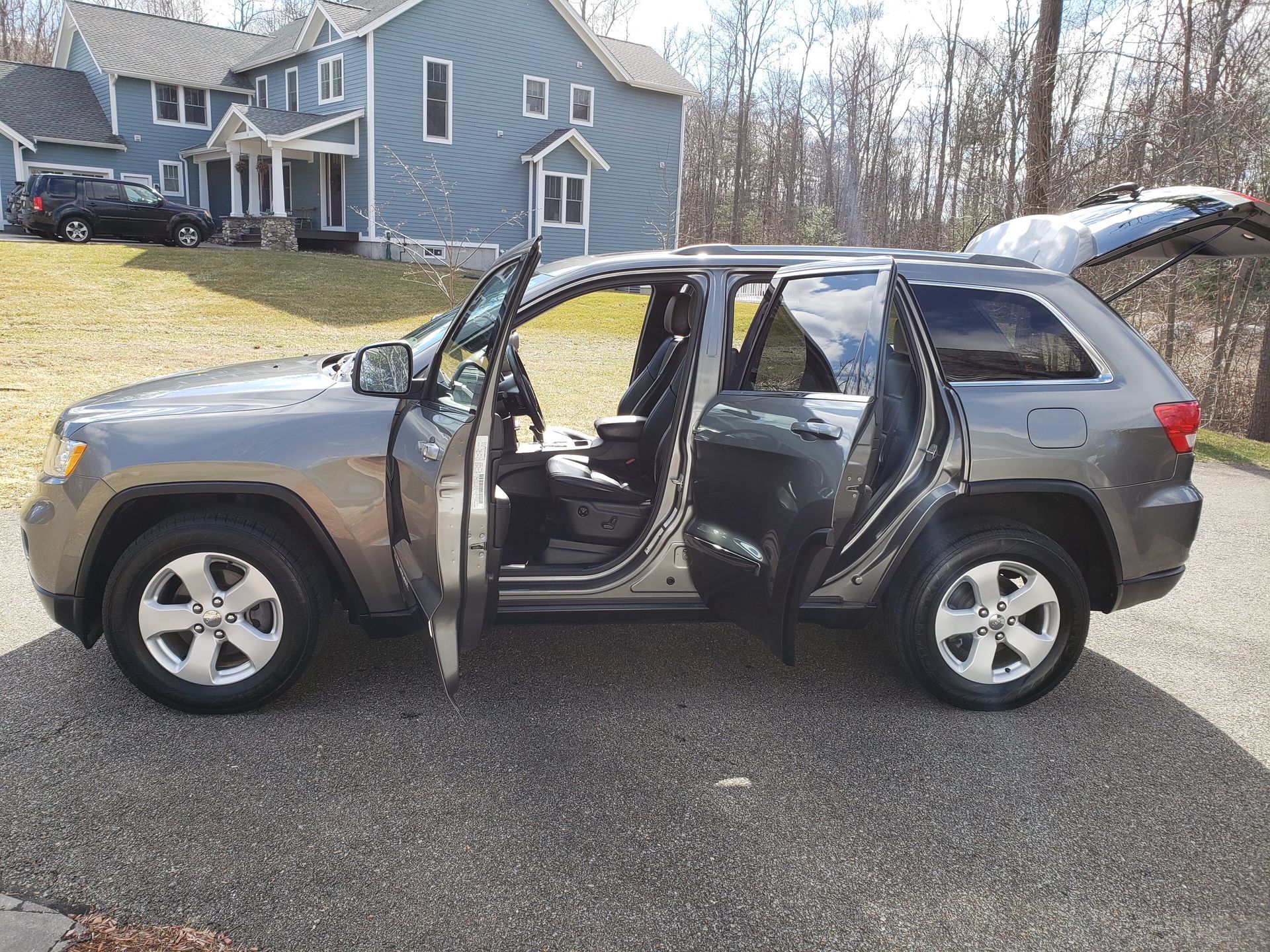 A jeep grand cherokee with its doors open is parked in front of a house.