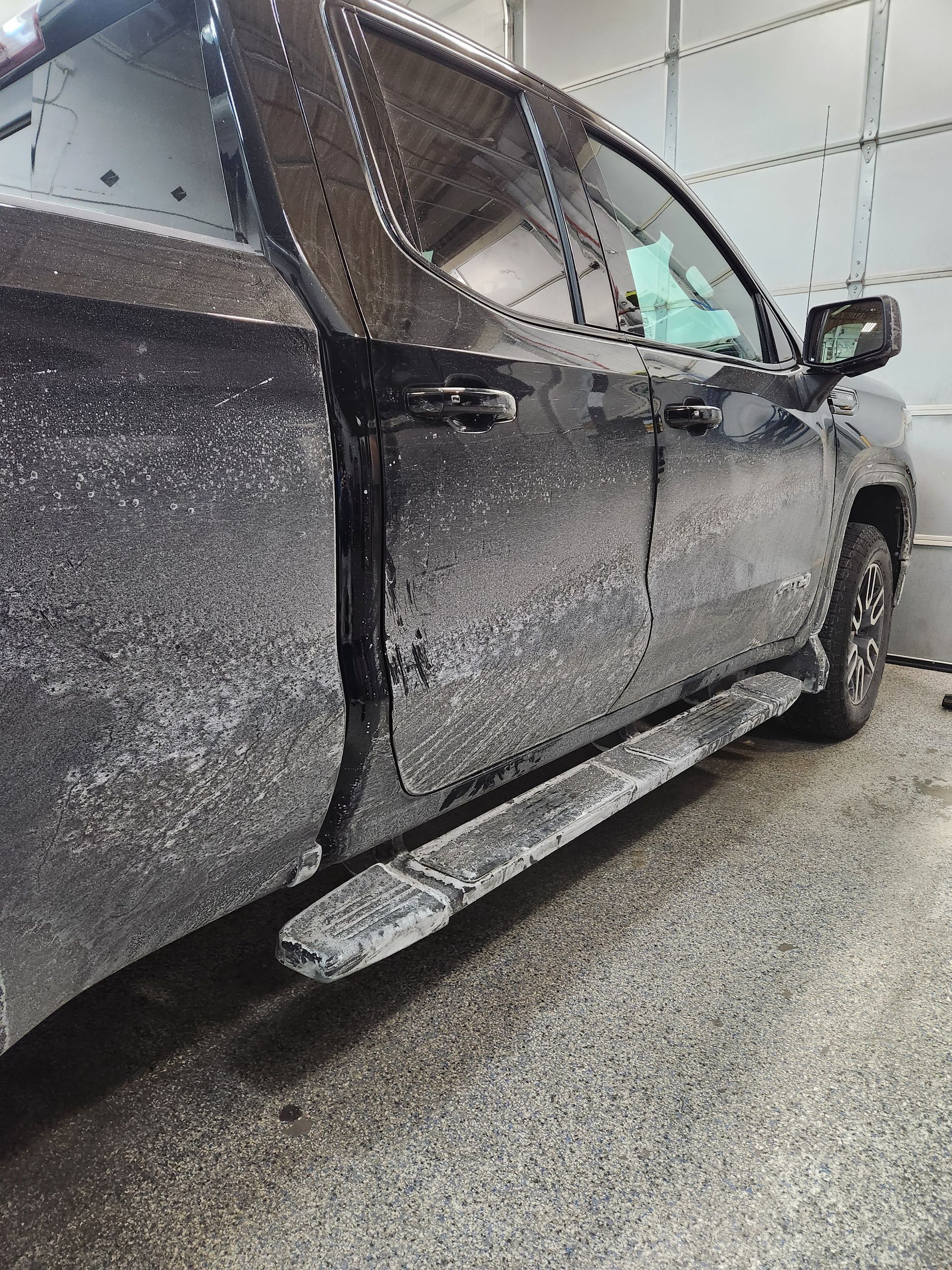 A dirty truck is parked in a garage.