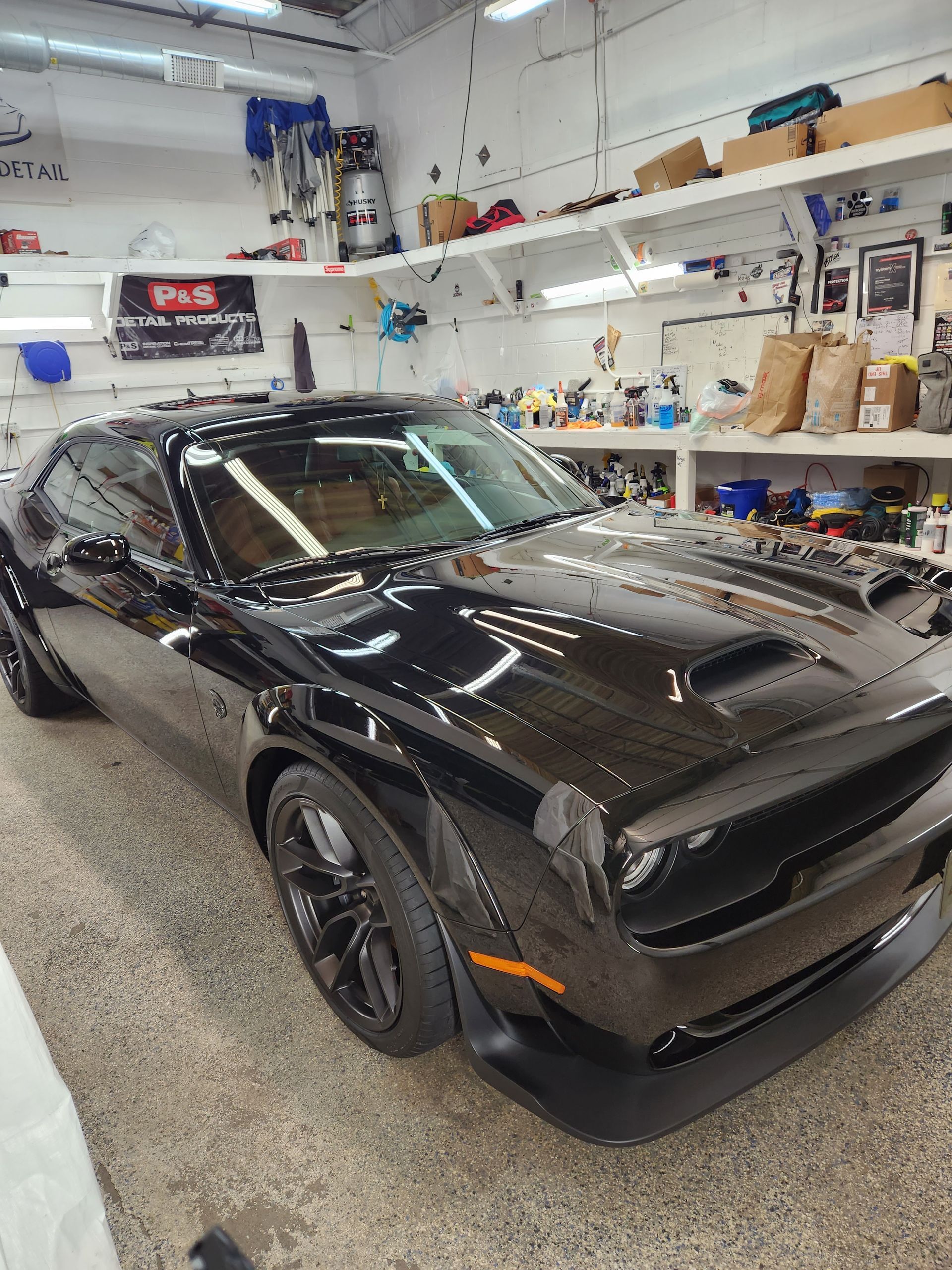 A black dodge challenger is parked in a garage.