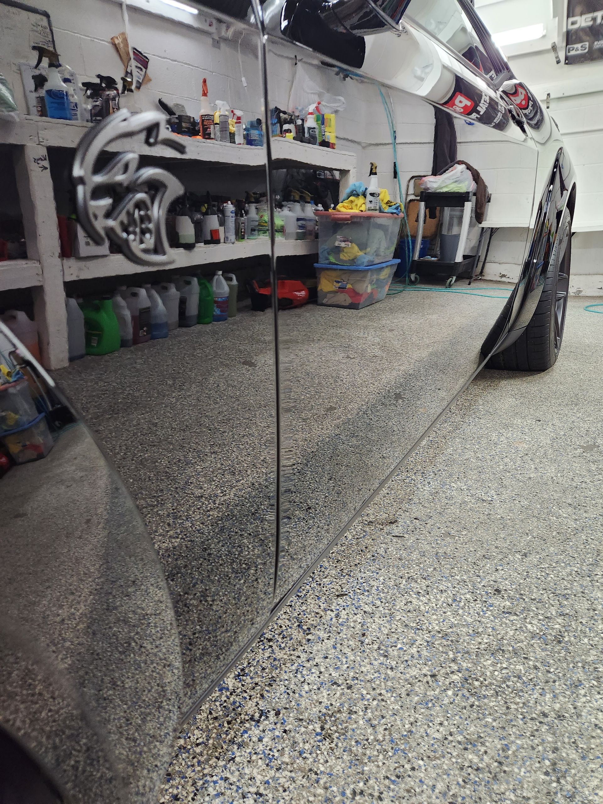 A car is parked in a garage with a reflection of the car in the mirror.