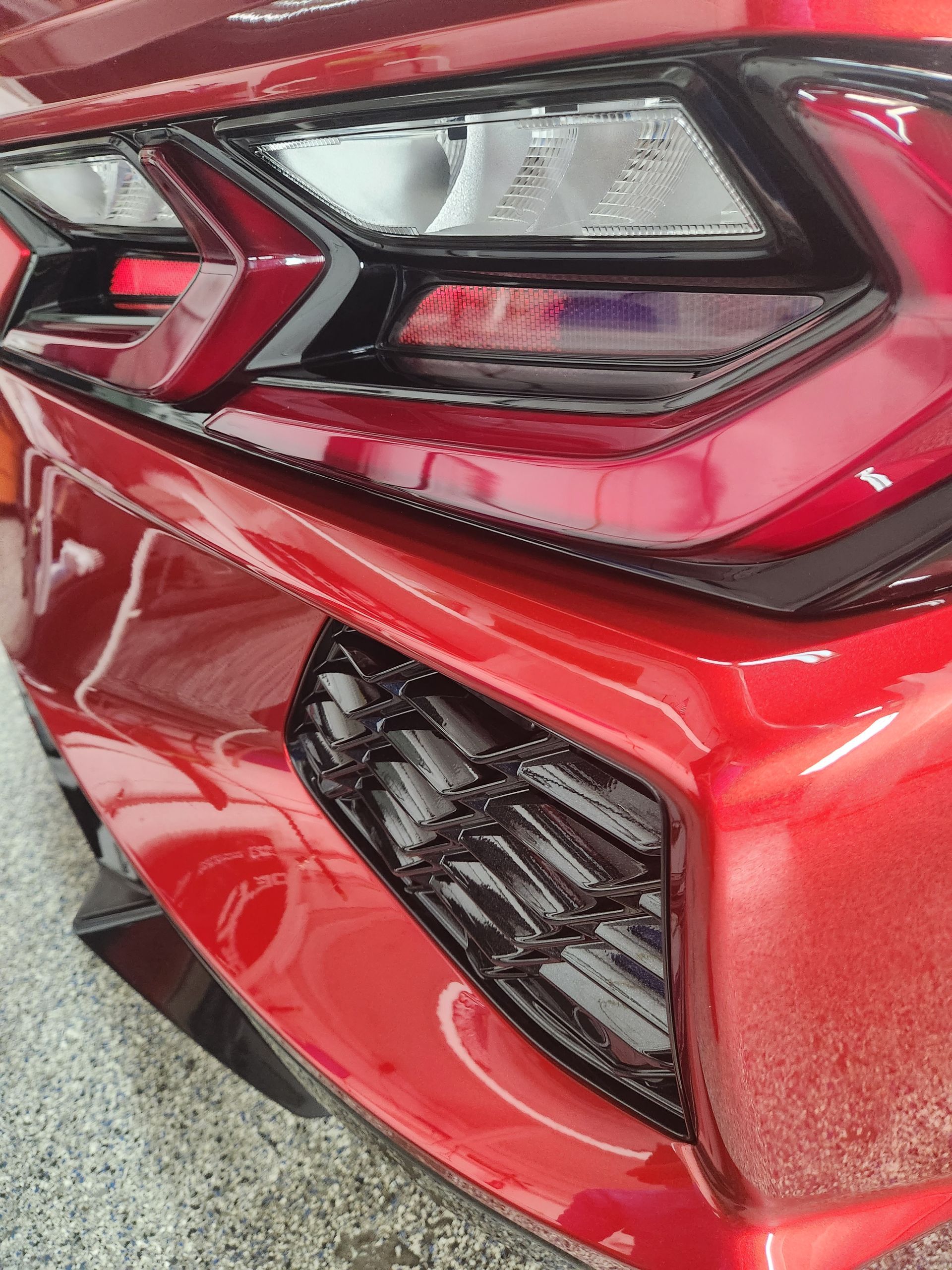 Close-up of a red sports car’s rear taillight and bumper with black trim and vent detail