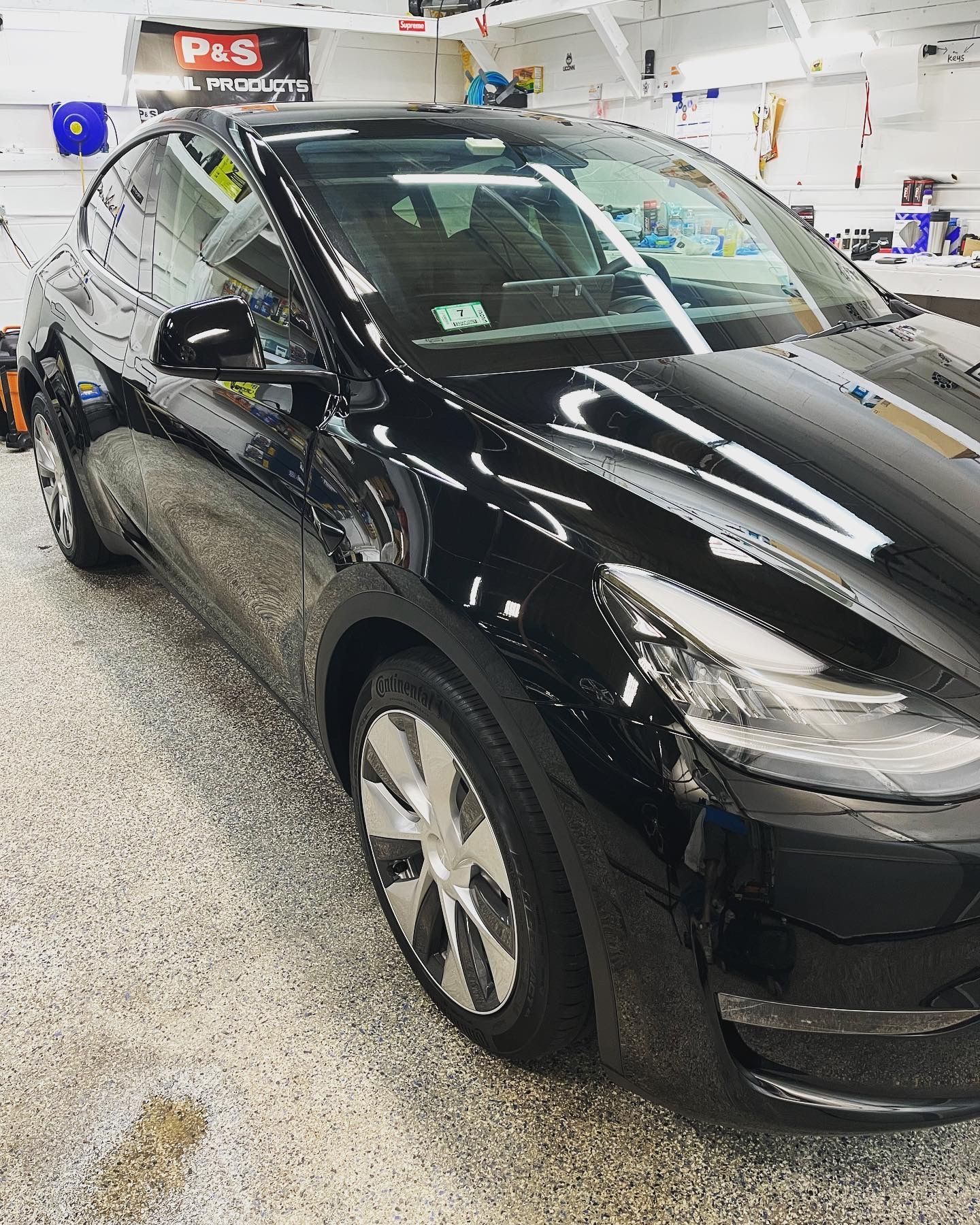 A black tesla model y is parked in a garage.