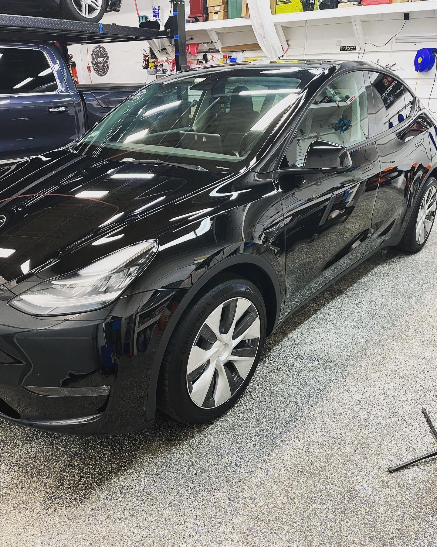 A black tesla model y is parked in a garage.