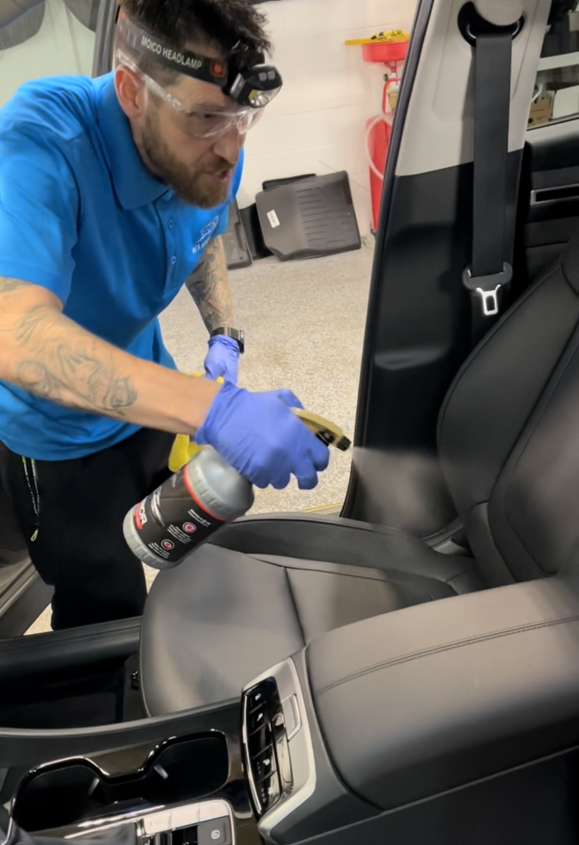 A man is cleaning the interior of a car with a spray bottle.