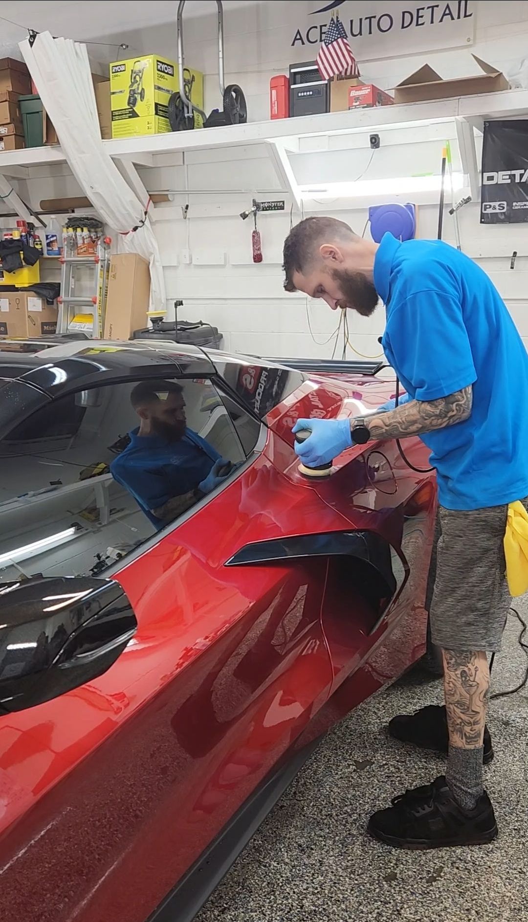 Worker polishing a red sports car in an auto detailing shop