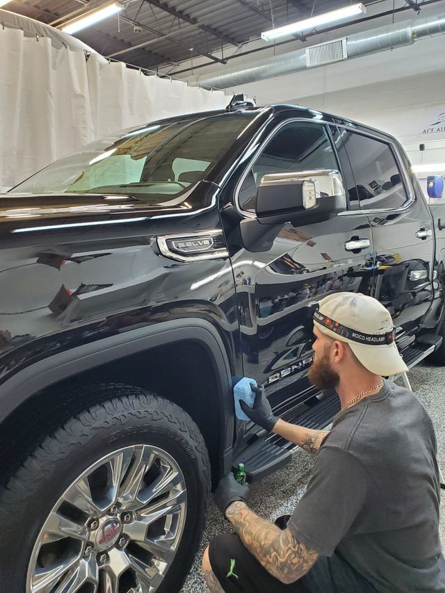 A man is polishing a black truck in a garage.