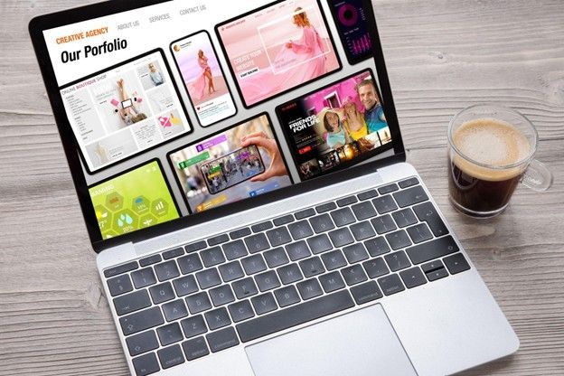 A laptop computer is sitting on a wooden table next to a cup of coffee.