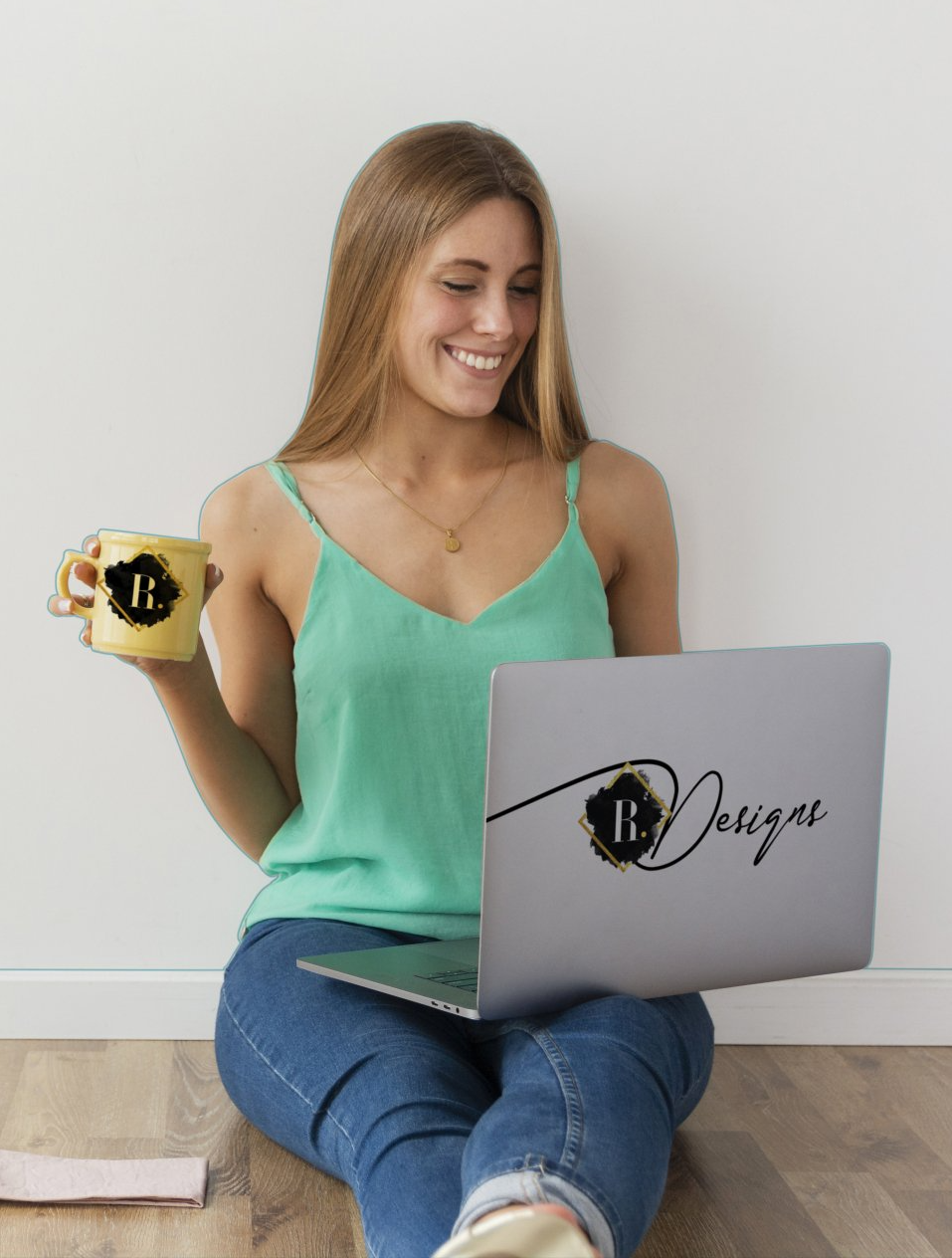 A woman is sitting on the floor using a laptop and holding a cup of coffee