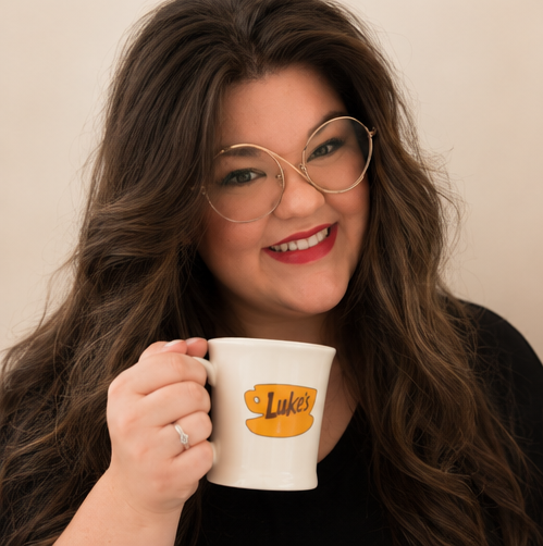 A woman is drinking a cup of coffee while holding a binder.