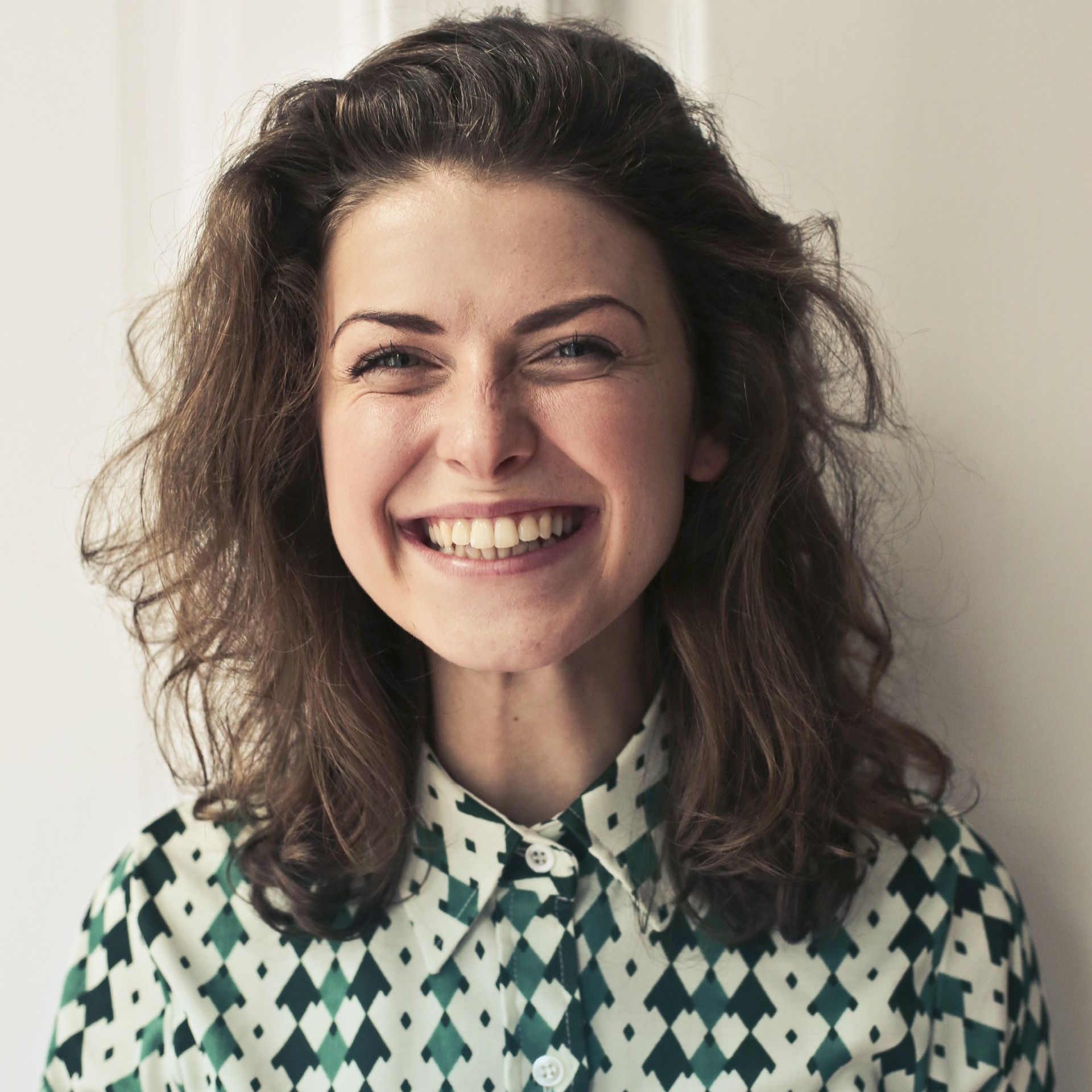 A woman wearing a green and white shirt is smiling