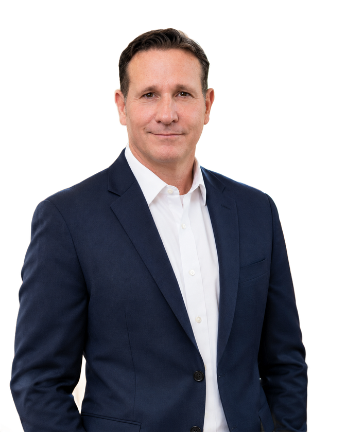 Man in navy suit and white shirt standing against a white background