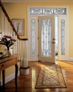 Sunlit foyer with a white front door, stained-glass panels, wooden floor, and runner rug